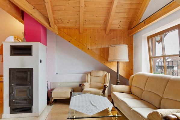 Ein Zimmer mit Holzboden, einer Couch, einem Sessel, einem Tisch und einem Fenster.