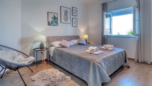 Una camera da letto con un letto, due lampade da comodino, una sedia, un tappeto e quadri appesi al muro.