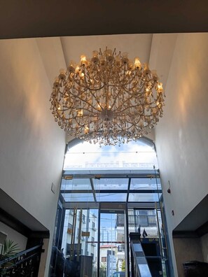 A modern interior with a large chandelier, glass doors leading to an outdoor area, and a staircase. - SWEIFIEH (Amman)