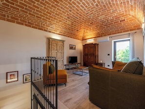 A living room with a brick ceiling, a television, a wooden cabinet, and a window. - Wonderful  villa for 5 guests with WIFI, private pool, patio, pets allowed and panoramic view (Asti)