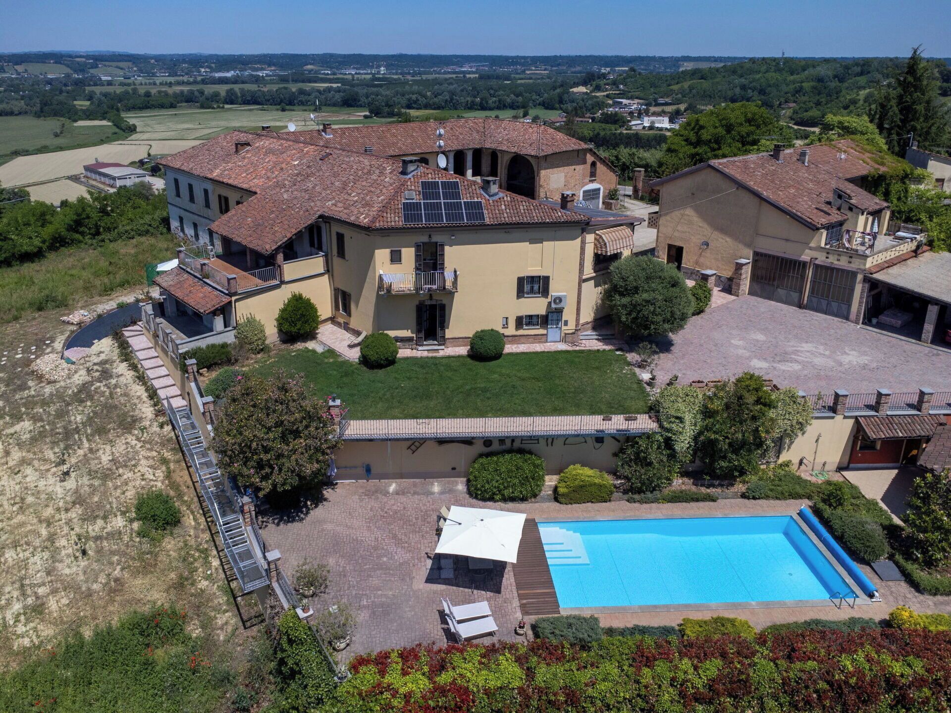 A large villa with a swimming pool, multiple balconies, and a spacious courtyard.