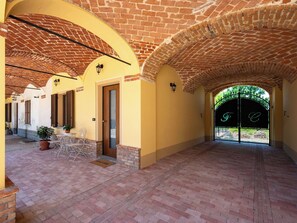 A covered corridor with brick arches, a door, and a gate with initials. - Wonderful  villa for 5 guests with WIFI, private pool, patio, pets allowed and panoramic view (Asti)