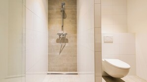 Un baño moderno con ducha, inodoro y paredes de azulejos.