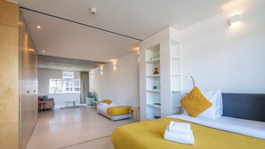 Una habitación de hotel moderna con una cama grande, un sofá, un escritorio y vistas de la ciudad.