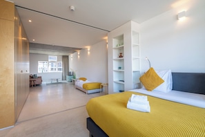 Une chambre dâhĂŽtel moderne, dotĂ©e dâun grand lit, dâun canapĂ©, dâun bureau et offrant une vue sur la ville.