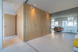 A spacious room with a large wardrobe, a sofa, and a window providing natural light.