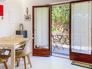 An open sliding glass door leading to an outdoor patio with a table and chairs. - Beautiful apartment for 3 guests with WIFI, A/C, TV and patio (Rosignano Marittimo)
