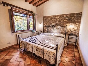 Ein Schlafzimmer mit Stewand, einem Bett mit Metallgestell, einem Fenster mit Vorhängen und einer Heizung.