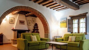 Ein gemütliches Wohnzimmer mit grünen Sofas, einem Kamin und einem rustikalen Backsteinbogen.