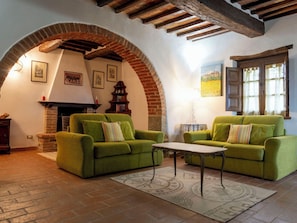 Ein gemütliches Wohnzimmer mit grünen Sofas, einem Kamin und einem rustikalen Backsteinbogen.