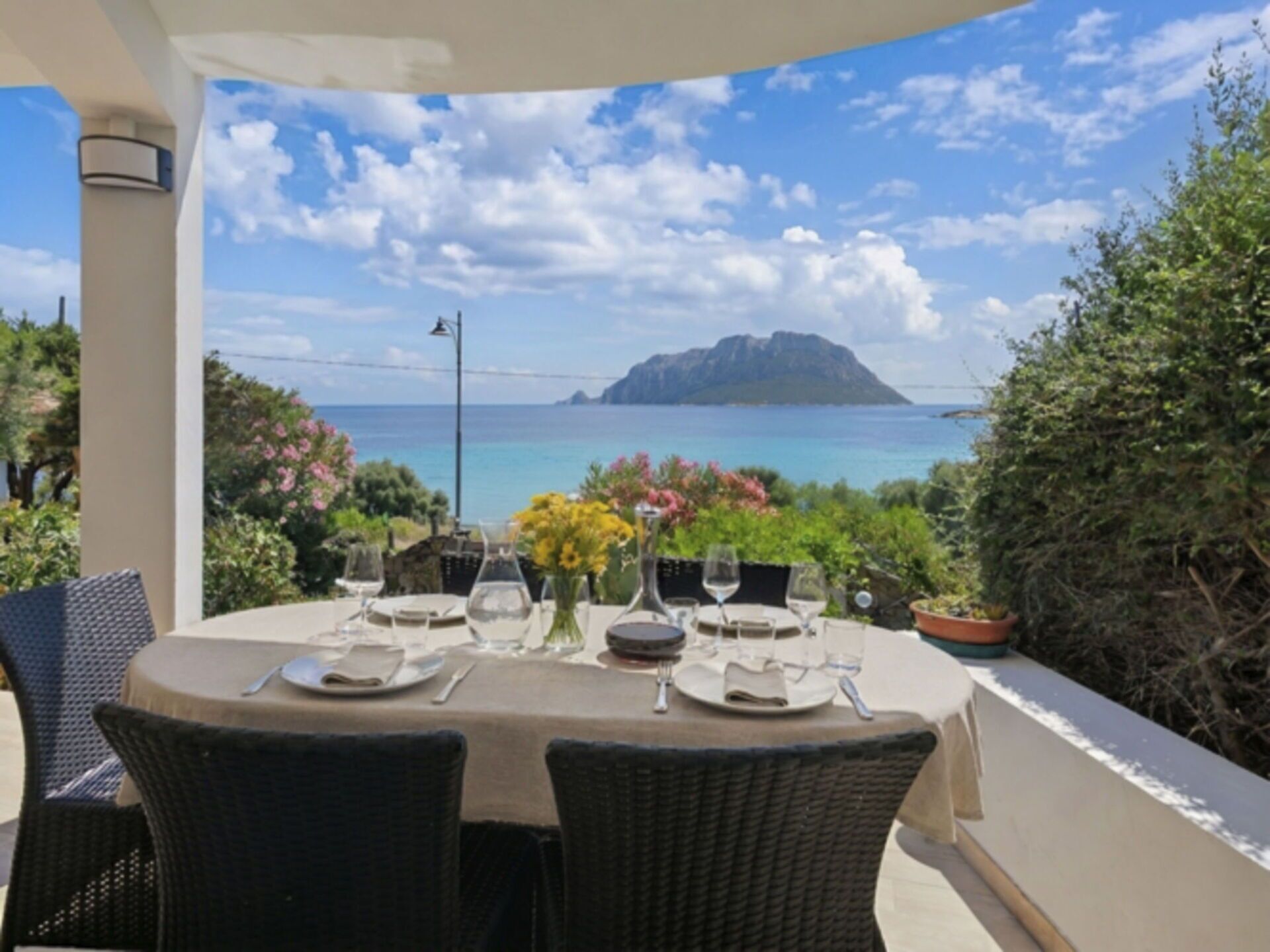 Mesa posta para refeição com vista para o mar e montanha.