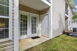 A residential building with a front door, a small porch, and a visible air conditioning unit.
