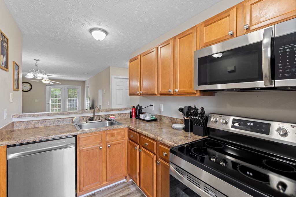 A kitchen with wooden cabinets, a stainless steel microwave, a stove, and a dishwasher.