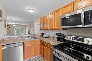 A kitchen with wooden cabinets, a stainless steel microwave, a stove, and a dishwasher.