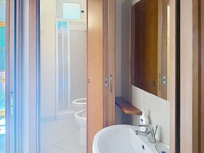 Une salle de bain équipée d’une douche, de toilettes, d’un lavabo et d’un meuble en bois.