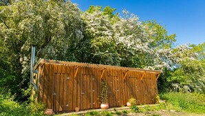 Una struttura in legno con tetto ondulato, immersa nel verde e circondata da alberi in fiore.