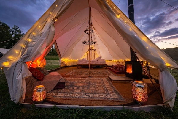 Twilight glow inside your bell tent, woodburner crackling and bed waiting