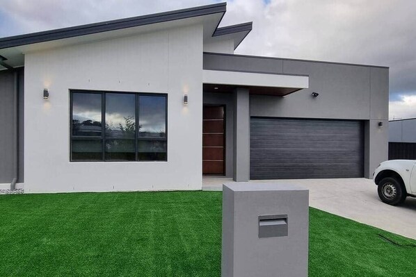 A modern two-story house with a garage, a well-maintained lawn, and a large window.