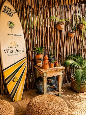 A surfboard with text, a bamboo wall, and potted plants.