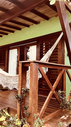 A wooden structure with a hammock, wooden beams, and a green wall.