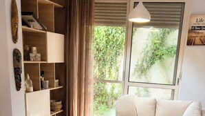 A modern living room with a sofa, a wooden dining table, and a bookshelf. - Bubu Garden Apartament - 3 Bedrooms (Durres)