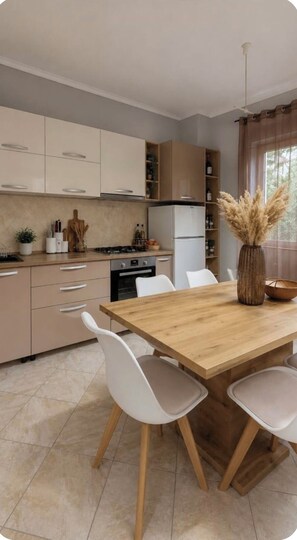 A modern kitchen with a wooden dining table, white chairs, and a vase with pampas grass. - Bubu Garden Apartament - 3 Bedrooms (Durres)
