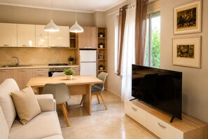 A modern kitchen with a dining area, a flat-screen TV, and a sofa. - Bubu Garden Apartament - 3 Bedrooms (Durres)