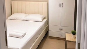 A bedroom with a bed, a wardrobe, and a small table with a plant. - Bubu Garden Apartament - 3 Bedrooms (Durres)