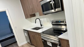 A compact kitchen with a microwave, oven, and dishwasher. - Two Bed Room & One Bathroom Secondary Suit (Calgary)