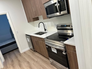 A compact kitchen with a microwave, oven, and dishwasher. - Two Bed Room & One Bathroom Secondary Suit (Calgary)