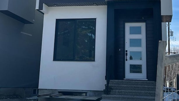 A modern two-story building with a balcony, large windows, and a white door. - Two Bed Room & One Bathroom Secondary Suit (Calgary)