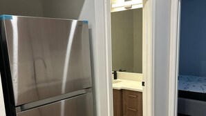 A kitchen with a stainless steel refrigerator, wooden cabinets, and a light-colored countertop. - Two Bed Room & One Bathroom Secondary Suit (Calgary)
