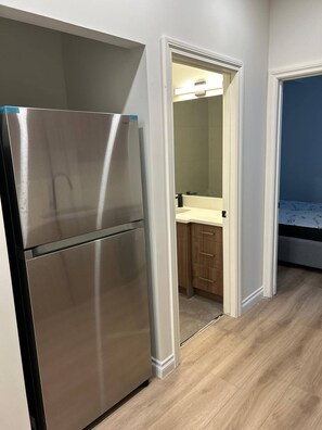 A kitchen with a stainless steel refrigerator, wooden cabinets, and a light-colored countertop. - Two Bed Room & One Bathroom Secondary Suit (Calgary)