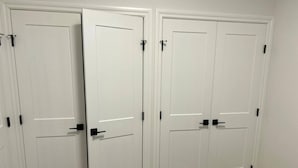 A set of white double doors with black handles and a visible gap between them. - Two Bed Room & One Bathroom Secondary Suit (Calgary)