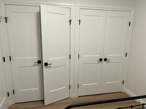 A set of white double doors with black handles and a visible gap between them. - Two Bed Room & One Bathroom Secondary Suit (Calgary)