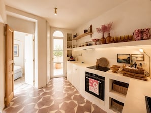 A kitchen with a geometric tile floor, white cabinetry, and a variety of kitchenware on shelves. - When in Portofino by "At Home" (Portofino)