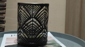 Une table ronde sur laquelle se trouve un objet noir à motifs, un objet blanc à pois rouges et un sol carrelé.