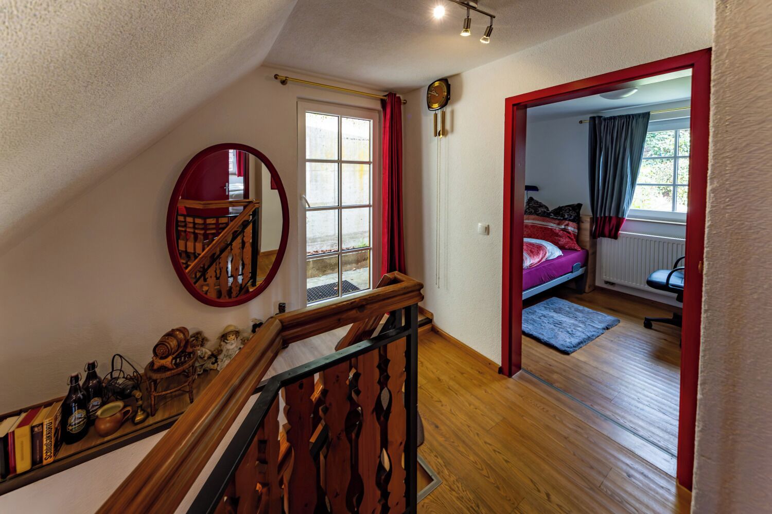 A staircase leading to a bedroom with a bed, a window, and a mirror.