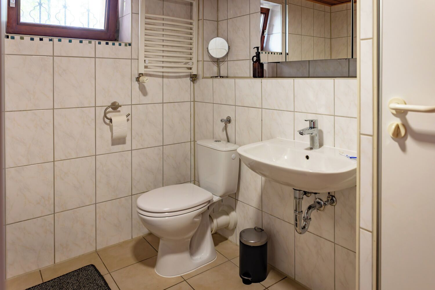 A small bathroom with a toilet, sink, and mirror.