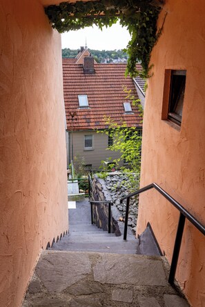 Kivestä rakennettu portaikko johtaa rakennukseen, jonka punatiilikatolla on ikkuna.