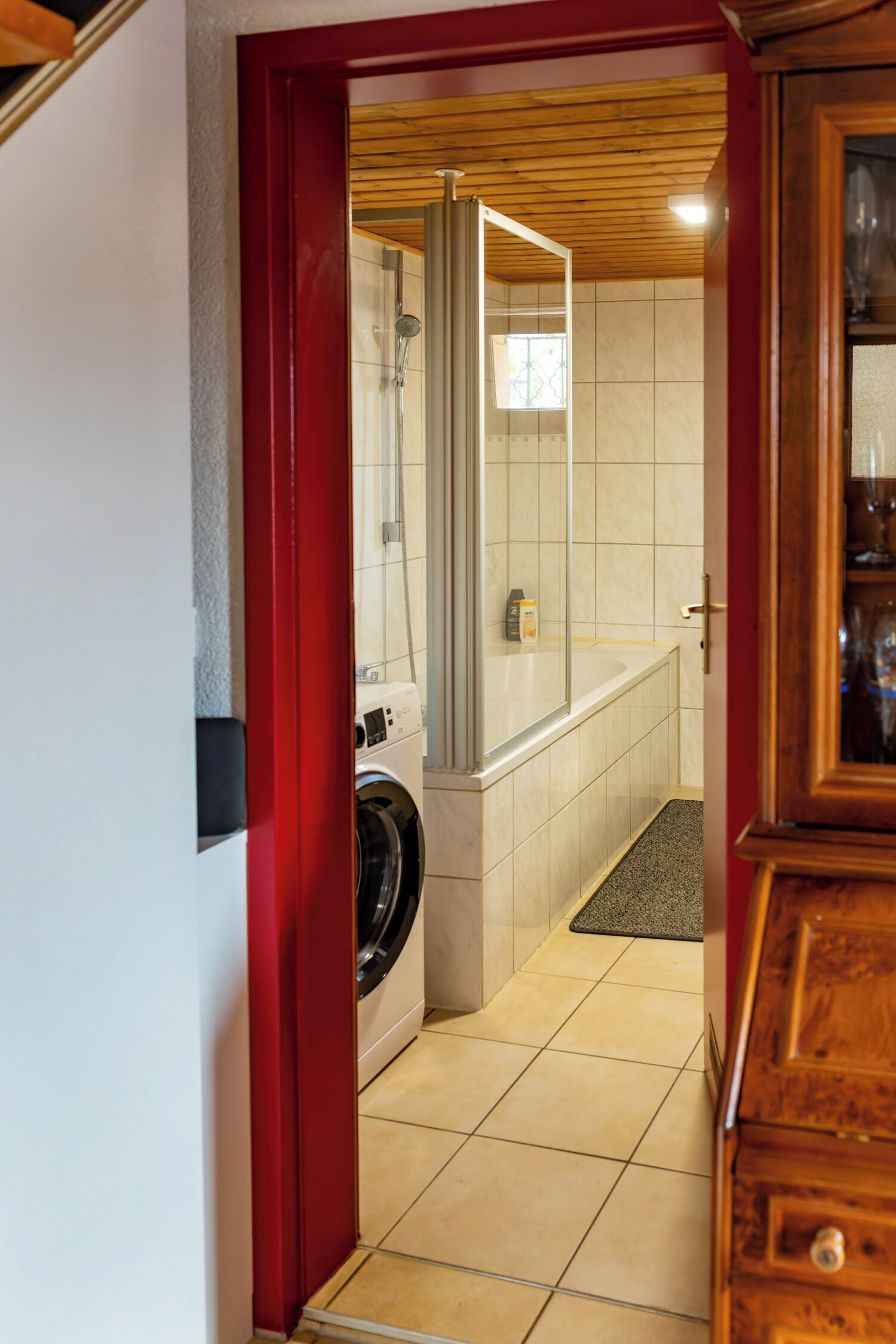 A laundry area with a washing machine, a shower, and a bathtub.