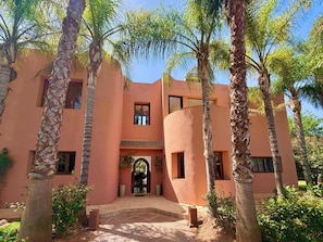 A building with a curved facade, multiple windows, and a central entrance with an archway. - Villa Amazura 6 Bedroom with Private Pool (Marrakech)