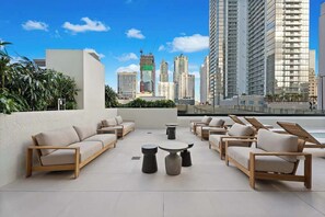 Eine Dachterrasse mit einer modernen Lounge, inklusive Sofas und Liegestühlen, und Blick auf die Stadtlandschaft.