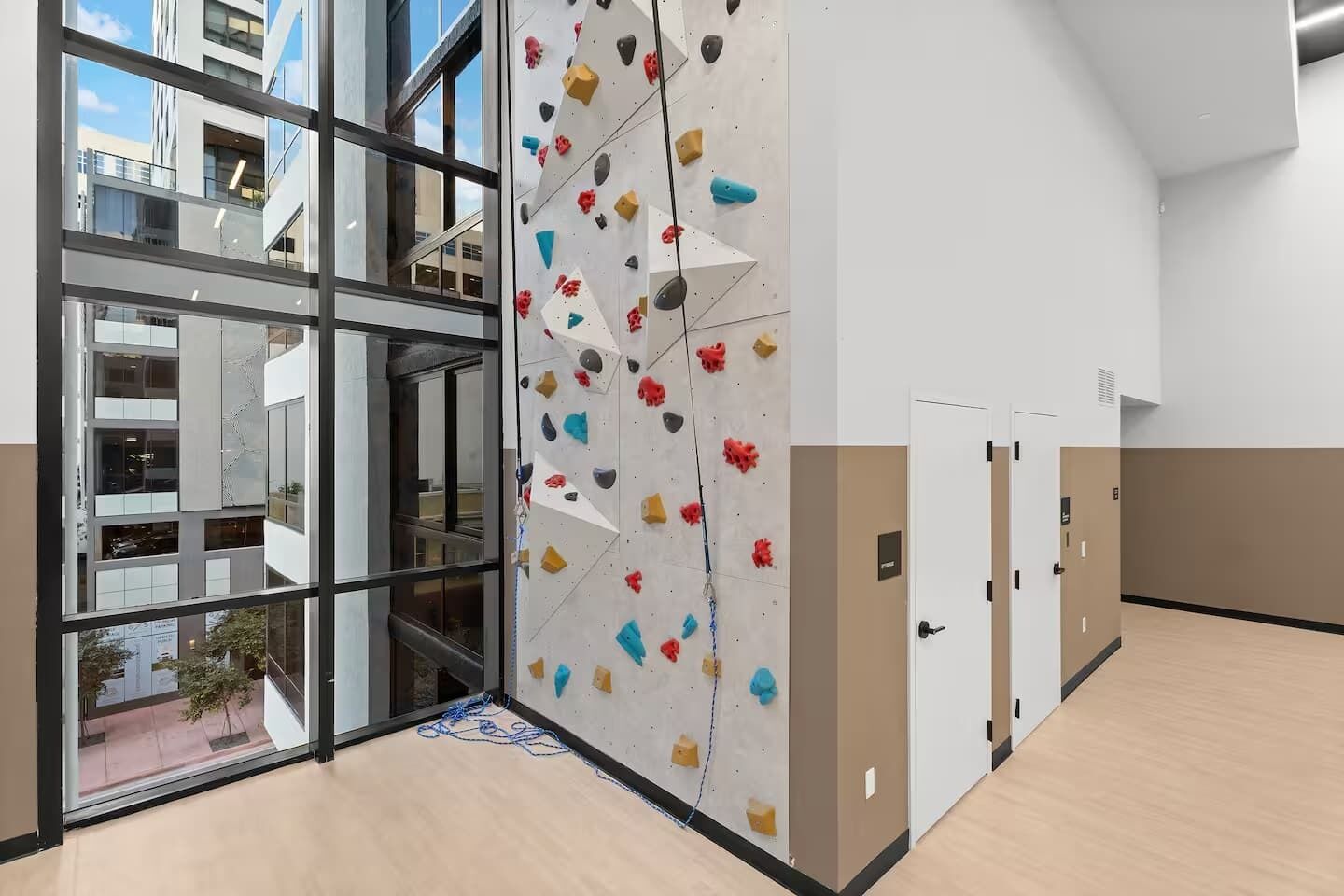 Een modern interieur met een klimmuur, grote ramen en uitzicht op een gebouw.