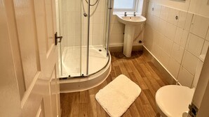 Un baño moderno con ducha acristalada, lavamanos e inodoro.