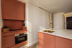 Eine moderne Küche mit Backofen, Spüle mit Goldarmatur und einem Muster-Spritzschutz.