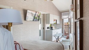 Una camera d'albergo moderna con un letto, una scrivania, una sedia, una TV e vista all'esterno.