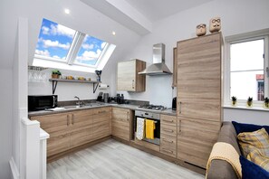 A modern kitchen with wooden cabinets, a built-in oven, a microwave, and a gas stove. - Captains Retreat, Whitby (Whitby)