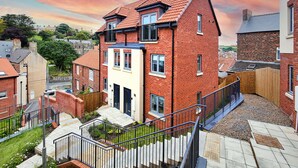 A residential building with a brick facade, a balcony, and a staircase leading to the entrance. - Captains Retreat, Whitby (Whitby)