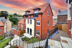 A residential building with a brick facade, a balcony, and a staircase leading to the entrance. - Captains Retreat, Whitby (Whitby)